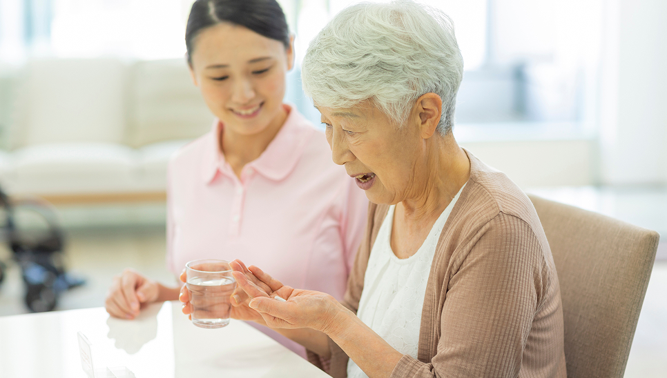 職員が高齢女性の服薬を見守る様子