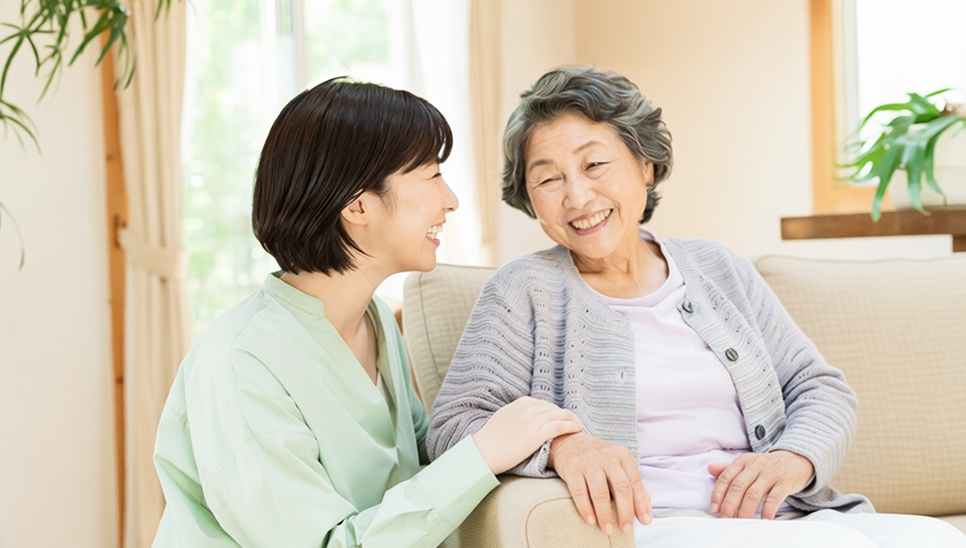ソファでくつろぎながら会話する高齢女性と女性
